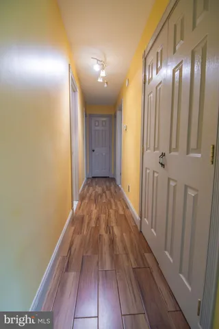 a view of a hallway with wooden floor and a bathroom
