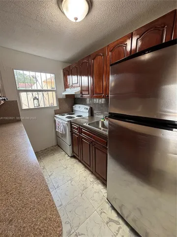 a kitchen with stainless steel appliances granite countertop a stove a sink and a refrigerator