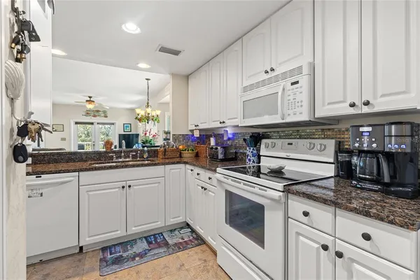 a kitchen with stainless steel appliances granite countertop a stove a sink and white cabinets