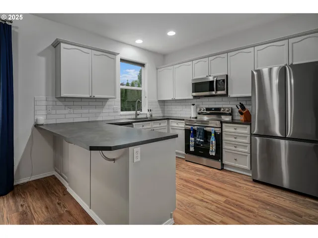 a kitchen with stainless steel appliances granite countertop a refrigerator a sink dishwasher a stove with wooden floor