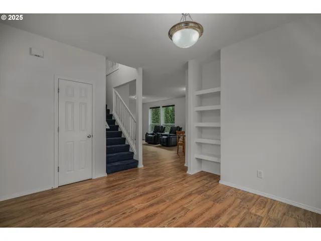 a view of an empty room with wooden floor and stairs