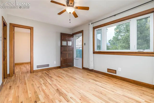 a view of an empty room with window and wooden floor