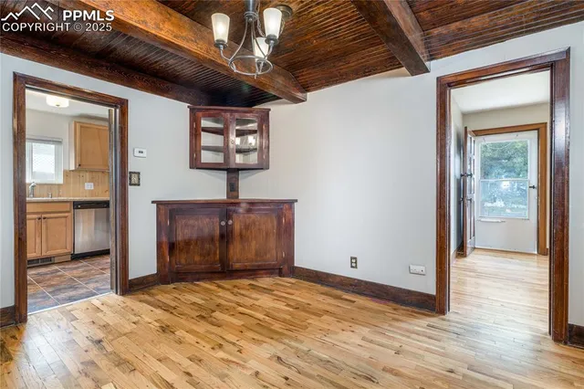 a view of a hallway with wooden floor and a kitchen