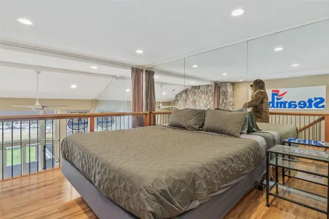 a large bedroom with a bed and wooden floor