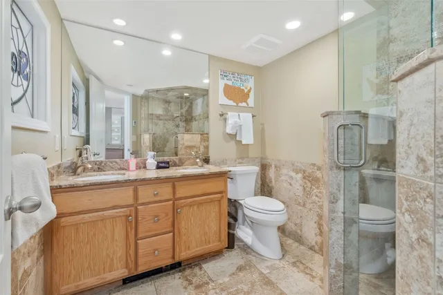 a bathroom with a granite countertop sink a toilet and a shower