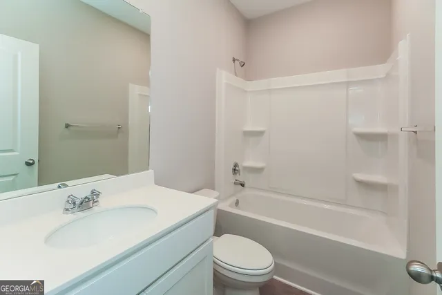 a bathroom with a bathtub shower sink vanity mirror and toilet