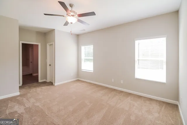 an empty room with windows and fan