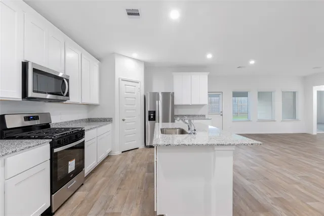 a large kitchen with granite countertop a stove top oven a sink a counter space and cabinets