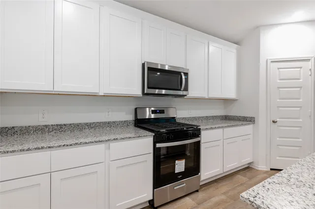a kitchen with granite countertop white cabinets and stainless steel appliances