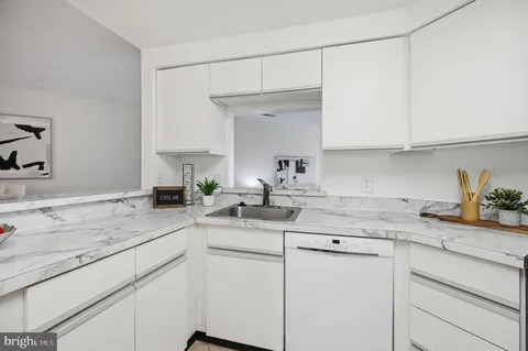a kitchen with a sink dishwasher a stove and white cabinets with wooden floor