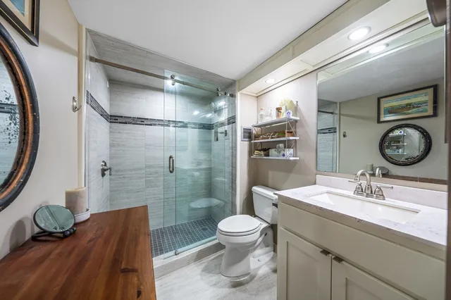 a bathroom with a granite countertop sink toilet a mirror and shower