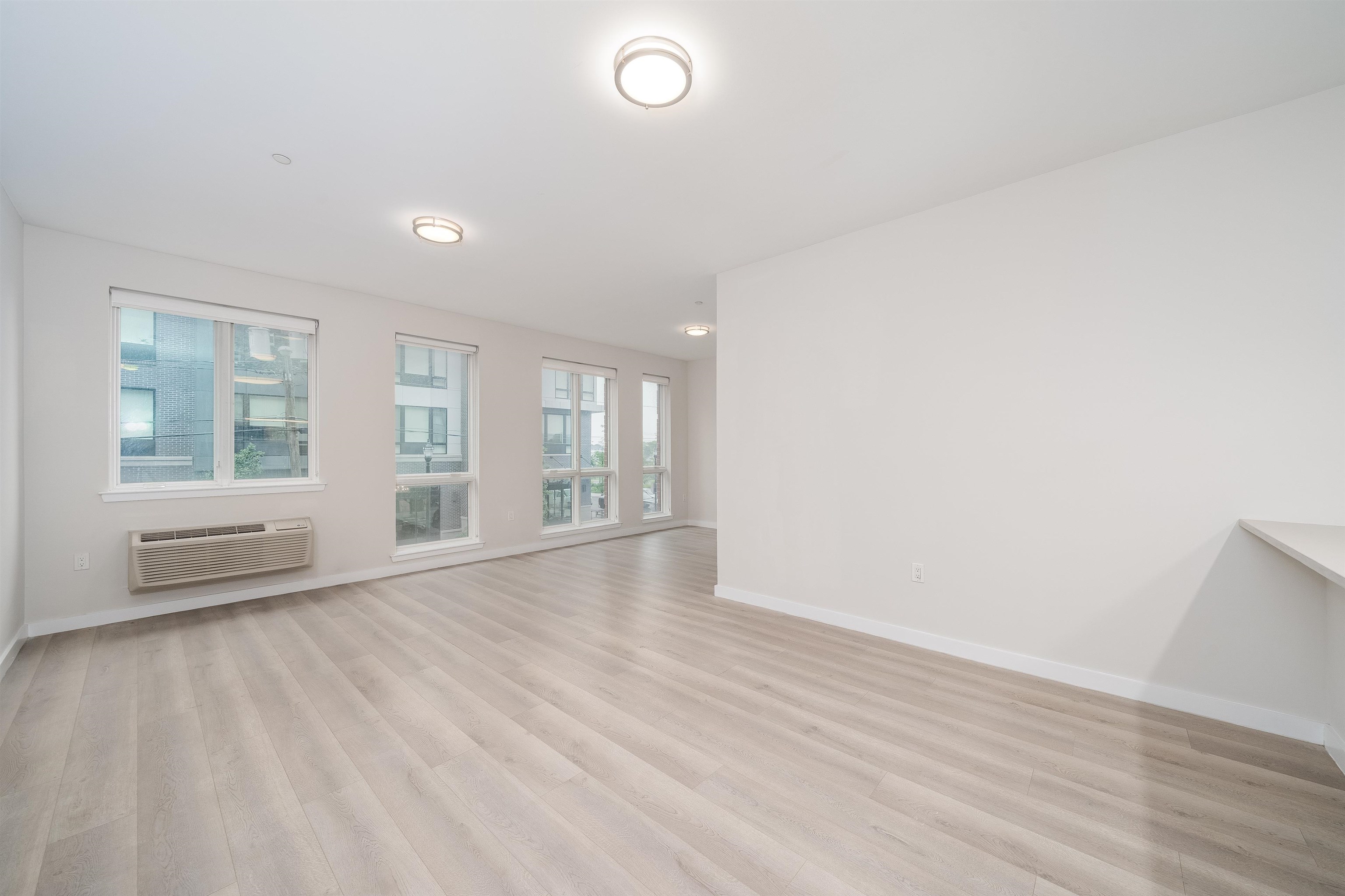 16 Bennett Street, Unit 504 Jersey City, NJ 07304 - Photo 5 of 24 an empty room with wooden floor and windows