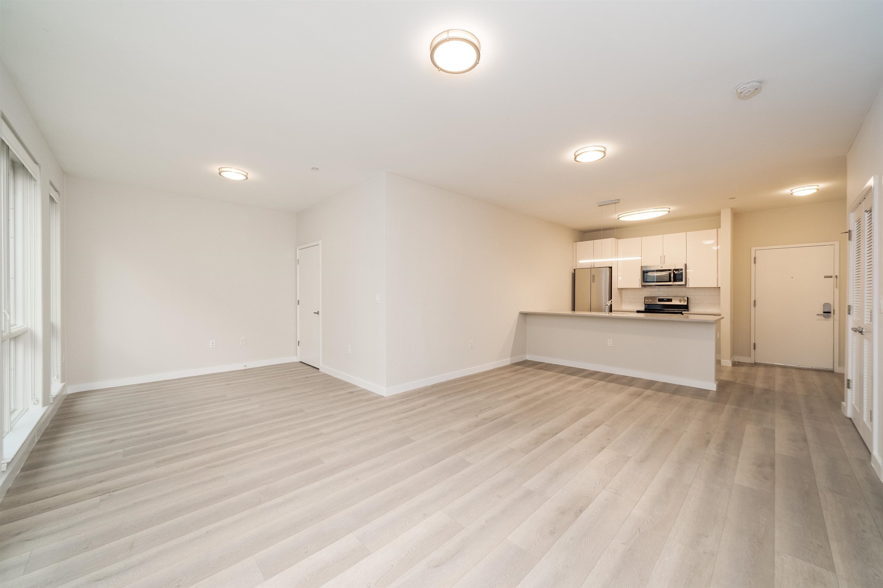 16 Bennett Street, Unit 504 Jersey City, NJ 07304 - Photo 6 of 24 a view of kitchen and empty room with wooden floor and windows