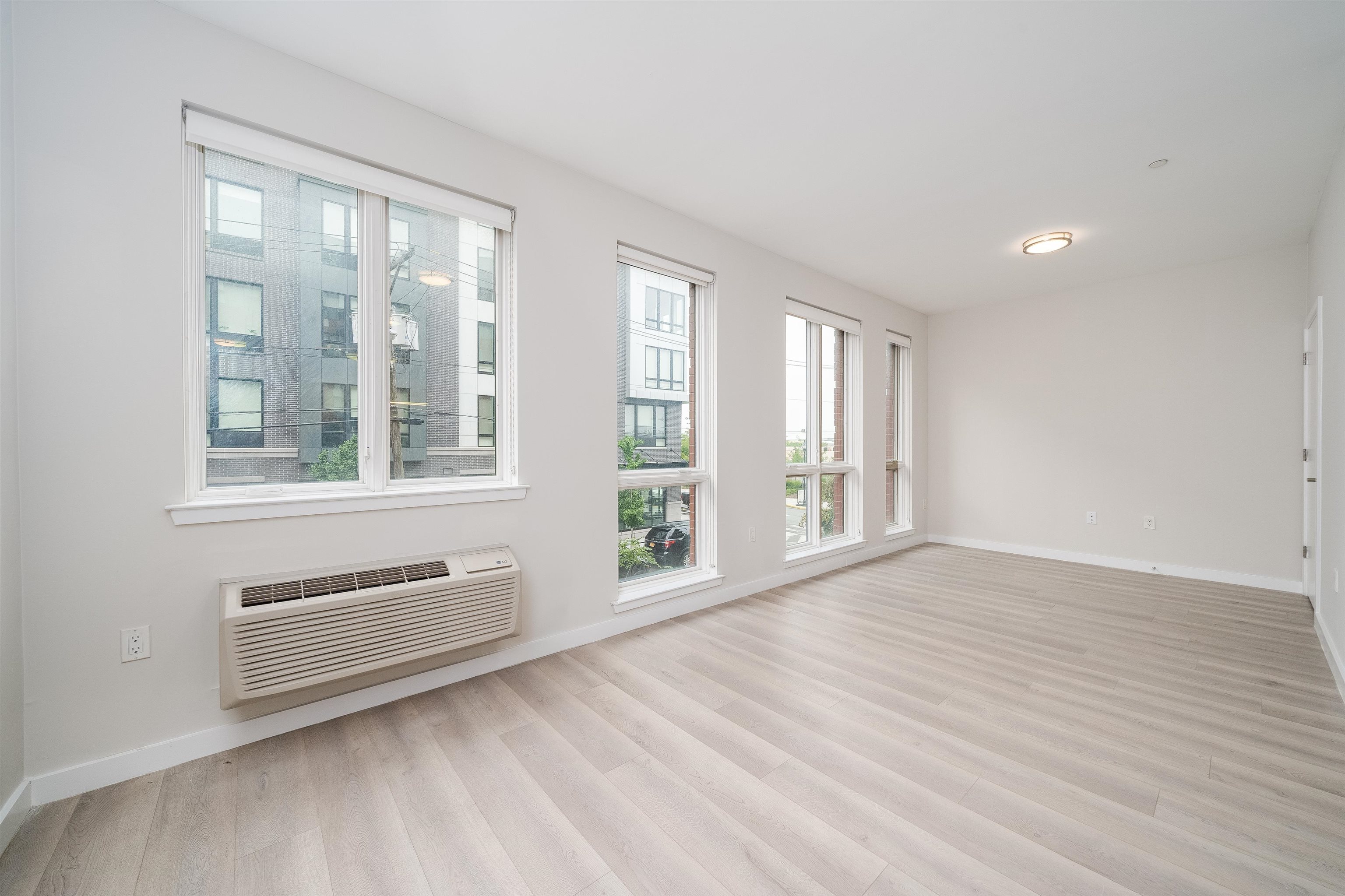 16 Bennett Street, Unit 504 Jersey City, NJ 07304 - Photo 7 of 24 a view of an empty room with a window and wooden floor