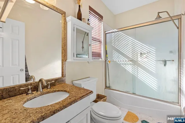 a bathroom with a granite countertop sink toilet a mirror and shower