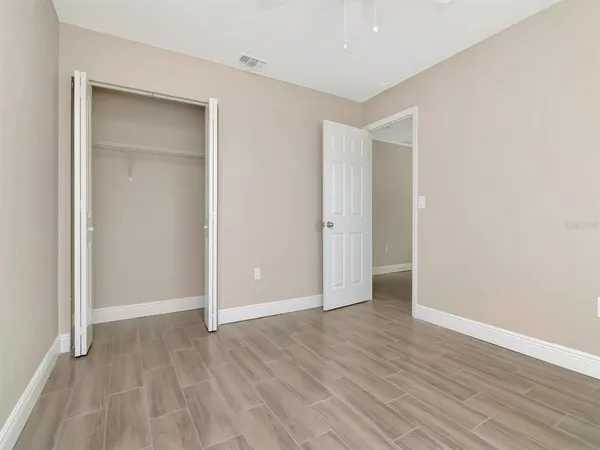 an empty room with wooden floor and a ceiling fan