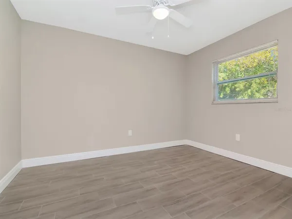 a view of an empty room with a window and wooden floor
