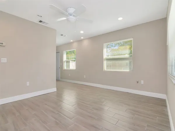 an empty room with wooden floor and windows