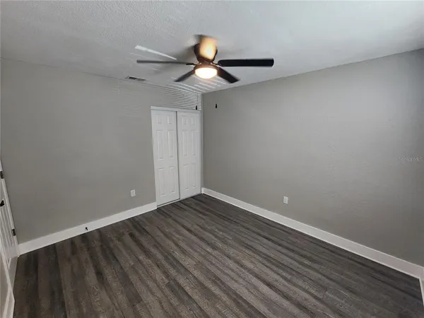 an empty room with wooden floor & closet area