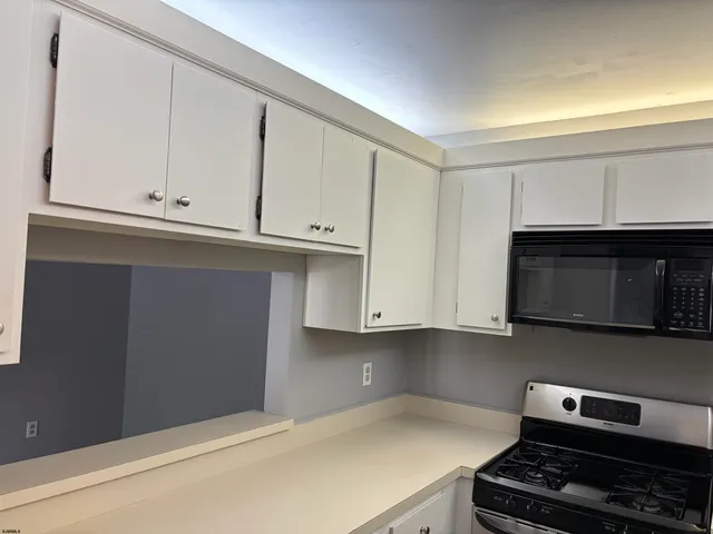 a kitchen with granite countertop white cabinets and black appliances