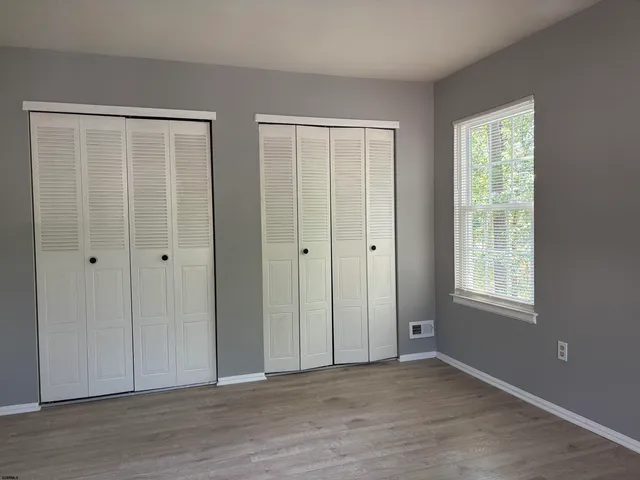 a view of an empty room with wooden floor and window