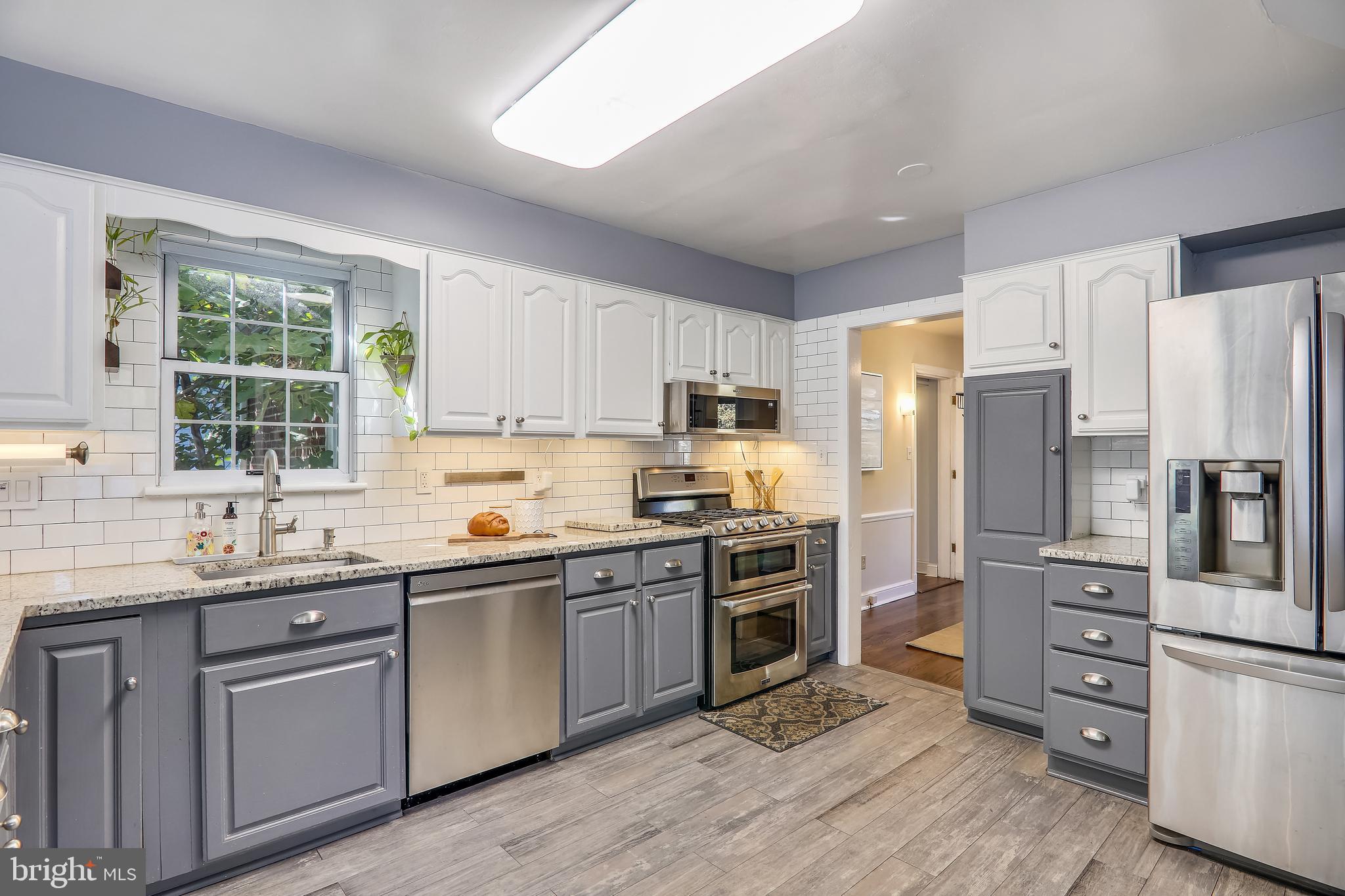 a kitchen with stainless steel appliances granite countertop a refrigerator a sink dishwasher a stove top oven a refrigerator with island and chairs