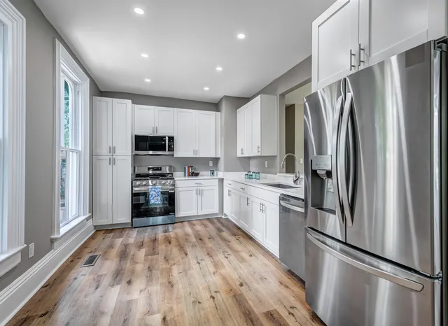a kitchen with white cabinets stainless steel appliances and a refrigerator