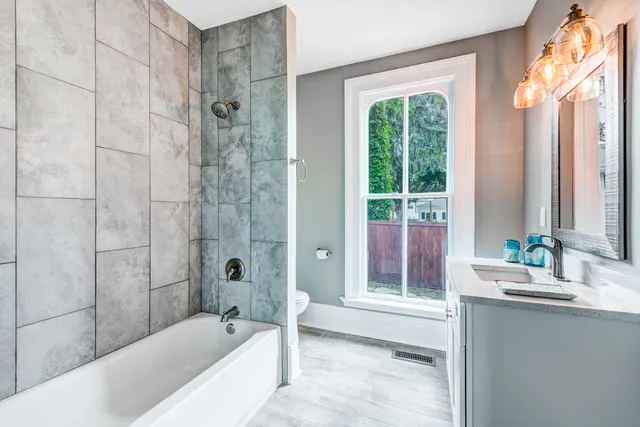 a bathroom with a granite countertop tub shower and sink