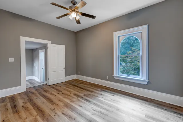 a view of a big room with wooden floor and a chandelier fan