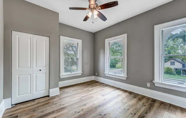 a view of an empty room with wooden floor and window