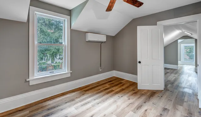 a view of an empty room with wooden floor and a window
