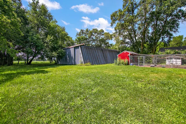 a view of a backyard with large trees and wooden fence