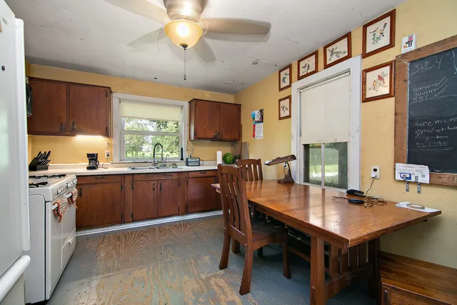 a kitchen with a stove a sink dishwasher a dining table and chairs with wooden floor