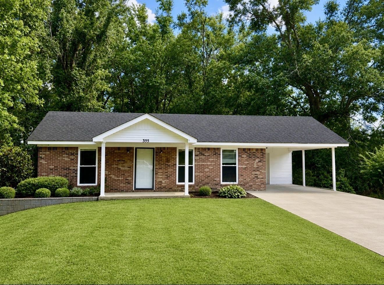 355 Purdy Road Selmer, TN 38375 - Photo 1 of 14 Brick exterior home featuring a dark shingle roof, white trim, and a covered front porch