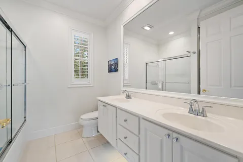 a bathroom with a double vanity sink toilet and a mirror