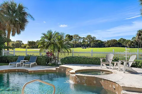 a view of a swimming pool with a lawn chairs under palm trees