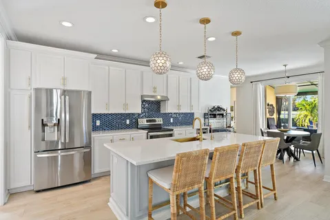 a kitchen with stainless steel appliances kitchen island granite countertop a dining table chairs and white cabinets
