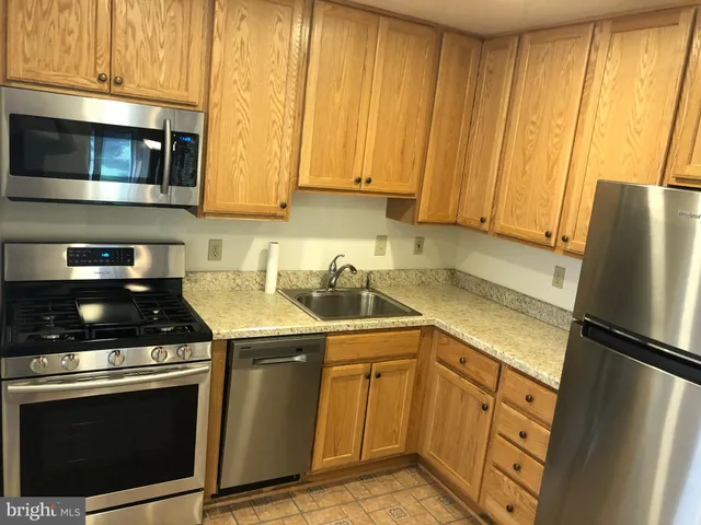 a kitchen with stainless steel appliances wooden cabinets and a stove top oven