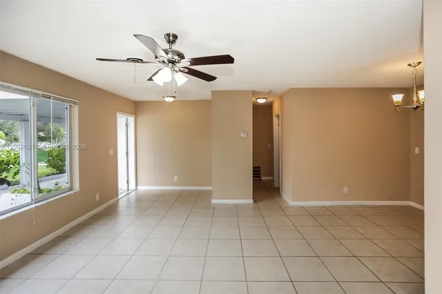 a view of an empty room and window and chandelier fan