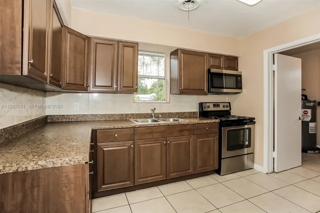 a kitchen with stainless steel appliances granite countertop a stove a sink and a microwave