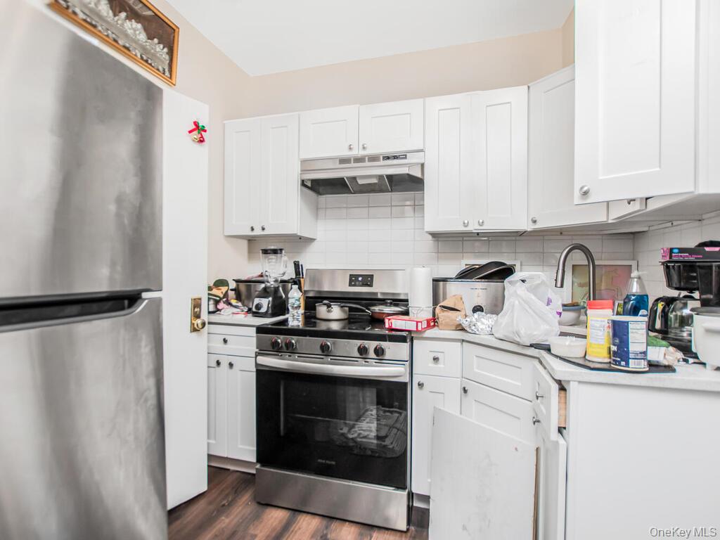 1406 White Plains Road Bronx, NY 10462 - Photo 11 of 43 a kitchen with stainless steel appliances a stove a refrigerator and cabinets