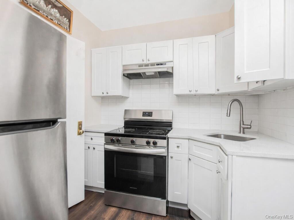 1406 White Plains Road Bronx, NY 10462 - Photo 34 of 43 a kitchen with stainless steel appliances white cabinets and a stove top oven