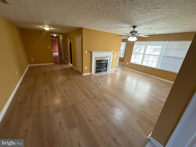 a view of a livingroom with wooden floor a ceiling fan and windows