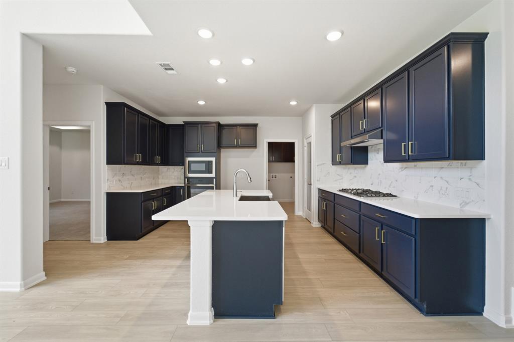 1908 Sangallo Lane Celina, TX 75009 - Photo 25 of 35 Modern kitchen featuring dark blue cabinetry, white countertops, a large center island, wood-finish flooring, and recessed lighting