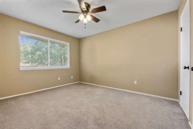 an empty room with a window and a fan