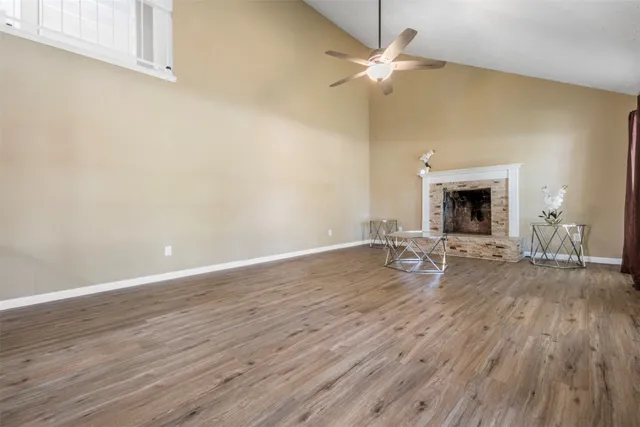 a view of a livingroom with wooden floor a ceiling fan and fireplace