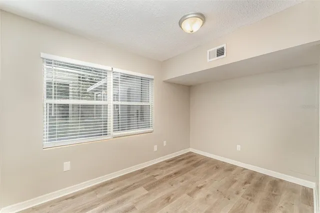 a view of empty room with wooden floor and windows