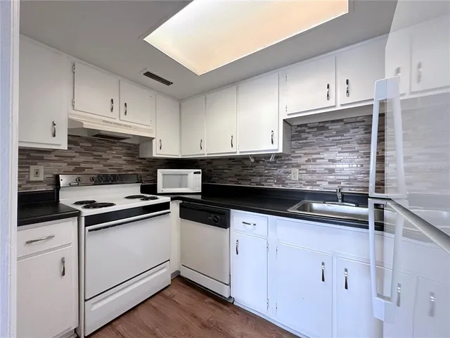 a kitchen with white cabinets stainless steel appliances and sink