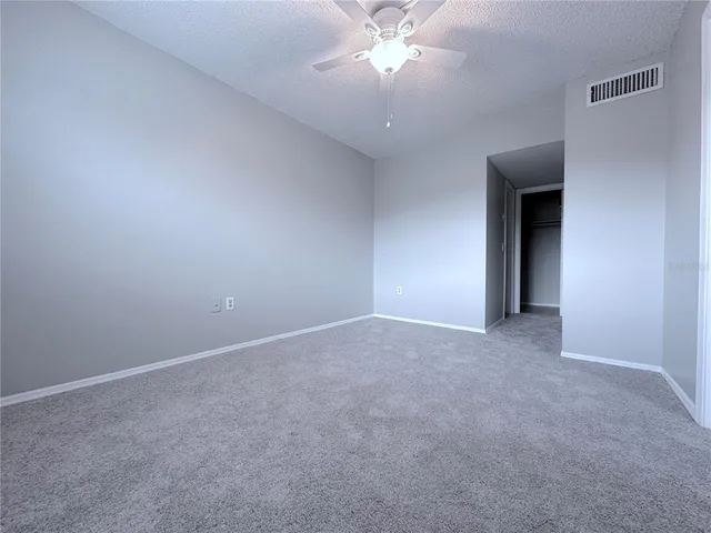 a view of an empty room with a chandelier fan