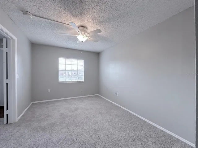 an empty room with a window and a fan